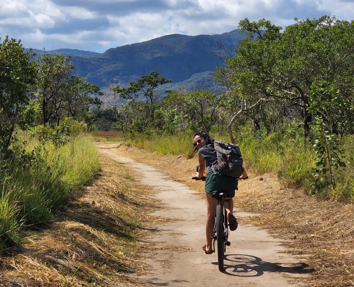 Pessoa fazendo trilha em paisagem montanhosa com equipamentos de camping