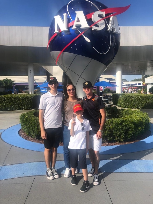 Família na entrada do Kennedy Space Center com globo da NASA