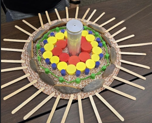 Colorful caps and popsicle sticks arranged in a circular sunburst pattern on a mirror base