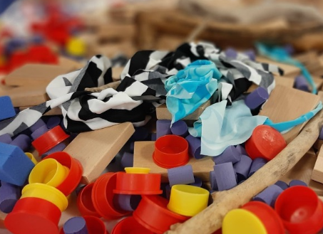 A colorful pile of caps, fabric scraps, and wooden pieces — loose parts materials