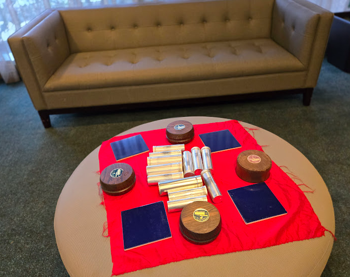 Loose parts materials laid out on a red cloth including mirrors, cylinders, and wooden pieces