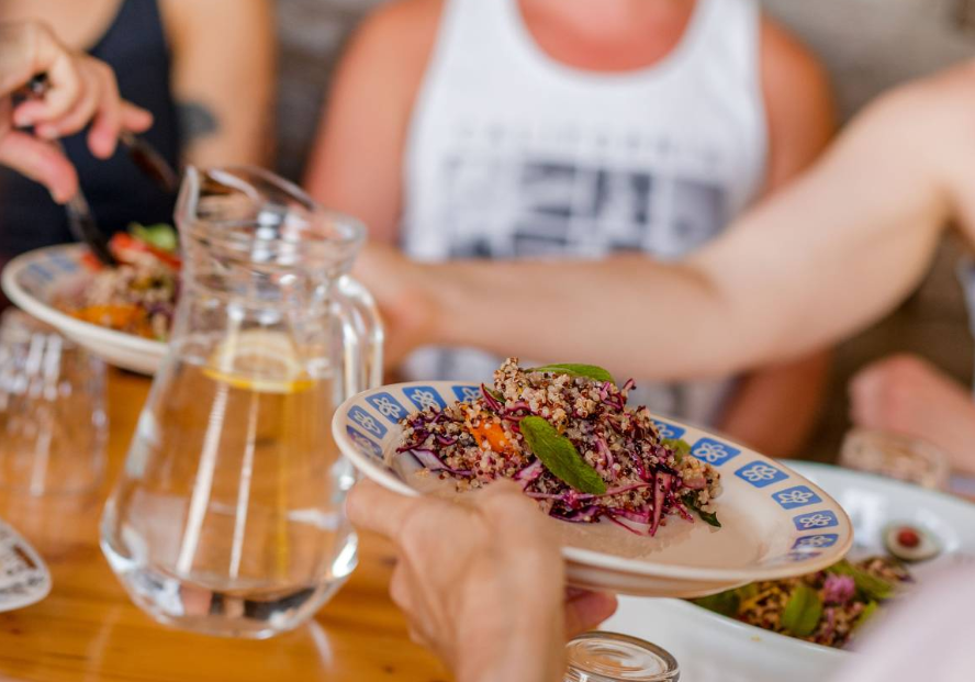 Close-up of a fresh quinoa salad being passed around at a communal dining table