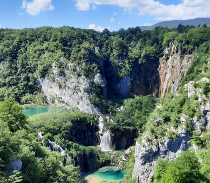 Panoramic aerial view of Plitvice Lakes with dramatic waterfalls cascading through lush green canyon