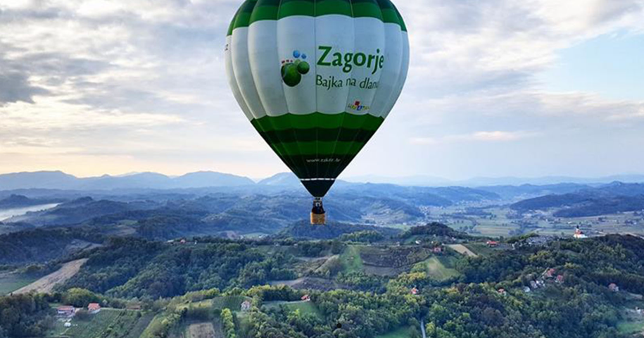 Zagorje hot air balloon floating above lush green rolling hills and valleys