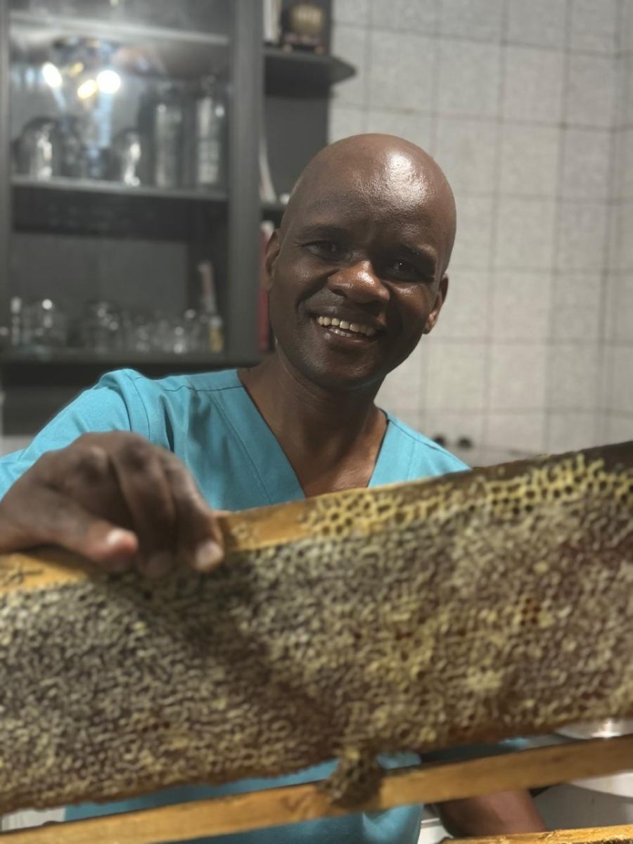 Practitioner at Arise & Shine holding a natural honeycomb frame