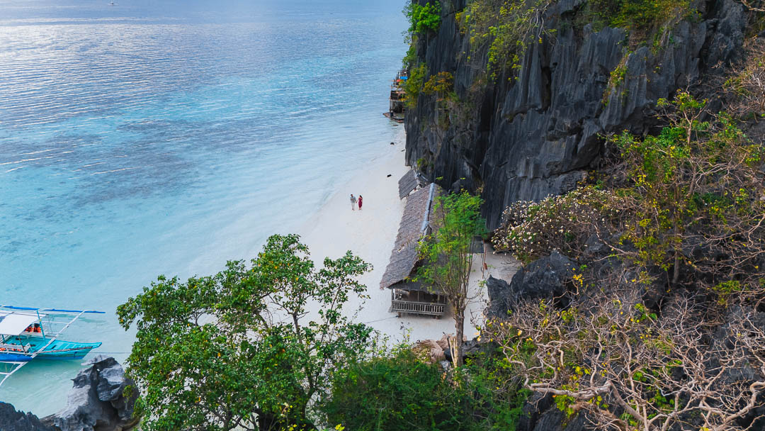 Coron Palawan white sand beach with limestone cliffs and traditional bangka boat