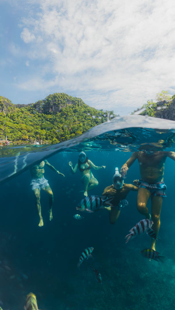 Snorkeling in Coron Palawan Philippines with tropical fish and limestone cliffs above water