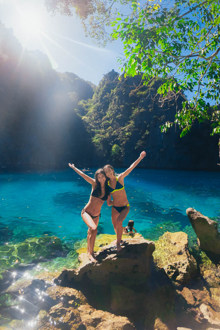 Two girls posing on rocks at Kayangan Lake Coron Palawan Philippines with stunning turquoise water and limestone cliffs