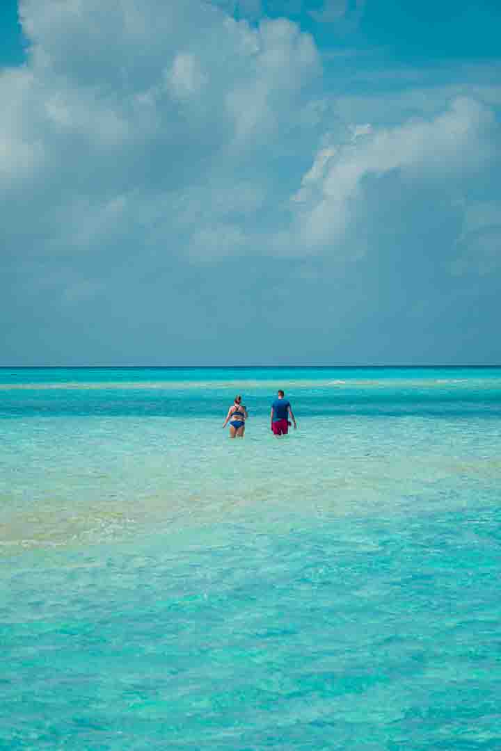 Couple wading in crystal turquoise waters of Balabac