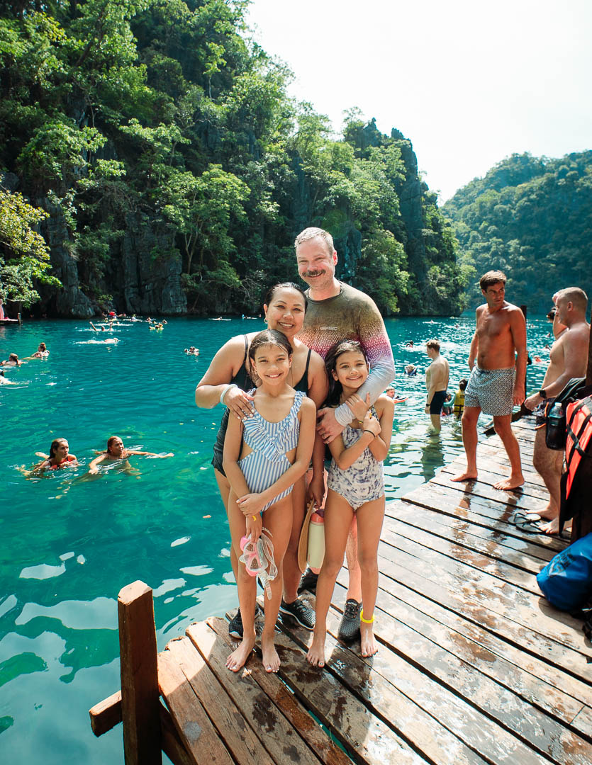 Family posing on wooden dock at Kayangan Lake Coron Palawan Philippines with turquoise water and limestone cliffs