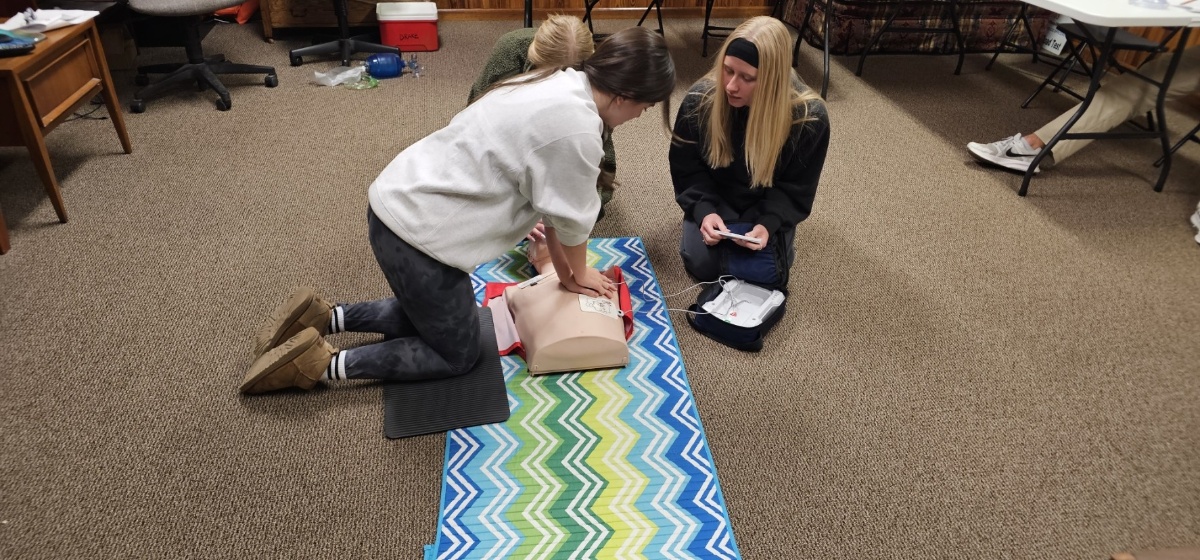 Students practicing CPR compressions on a manikin with AED trainer during a Tallahassee certification class
