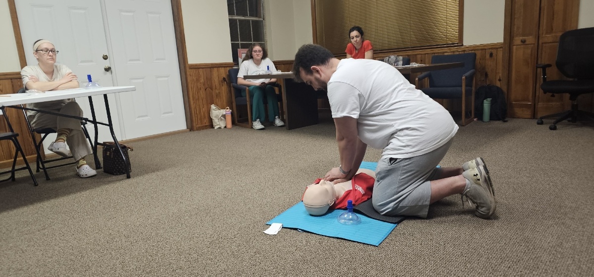CPR instructor demonstrating chest compressions on a manikin during a Tallahassee certification class