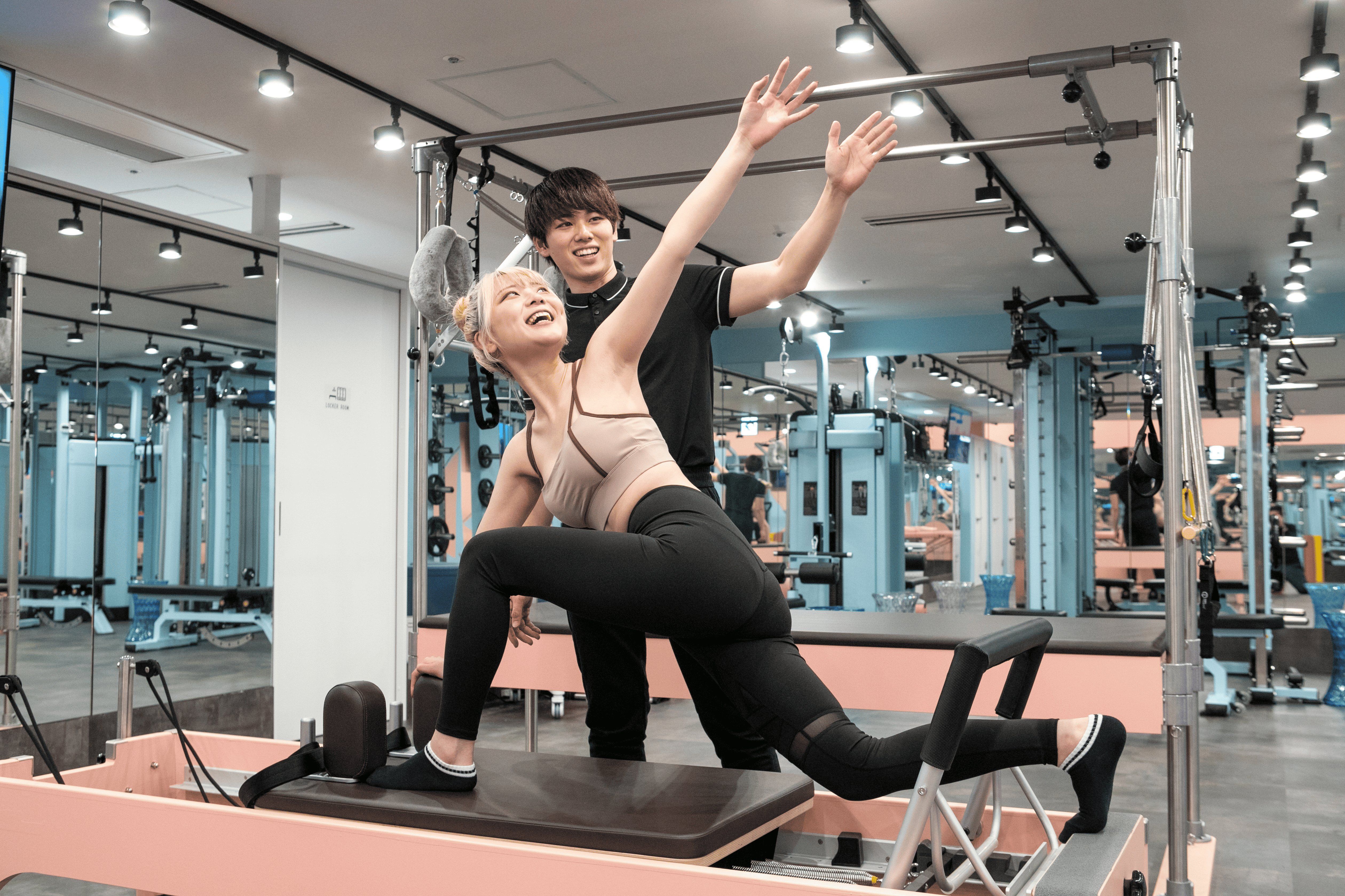 トレーナーとクライアントが笑顔でストレッチをしている様子