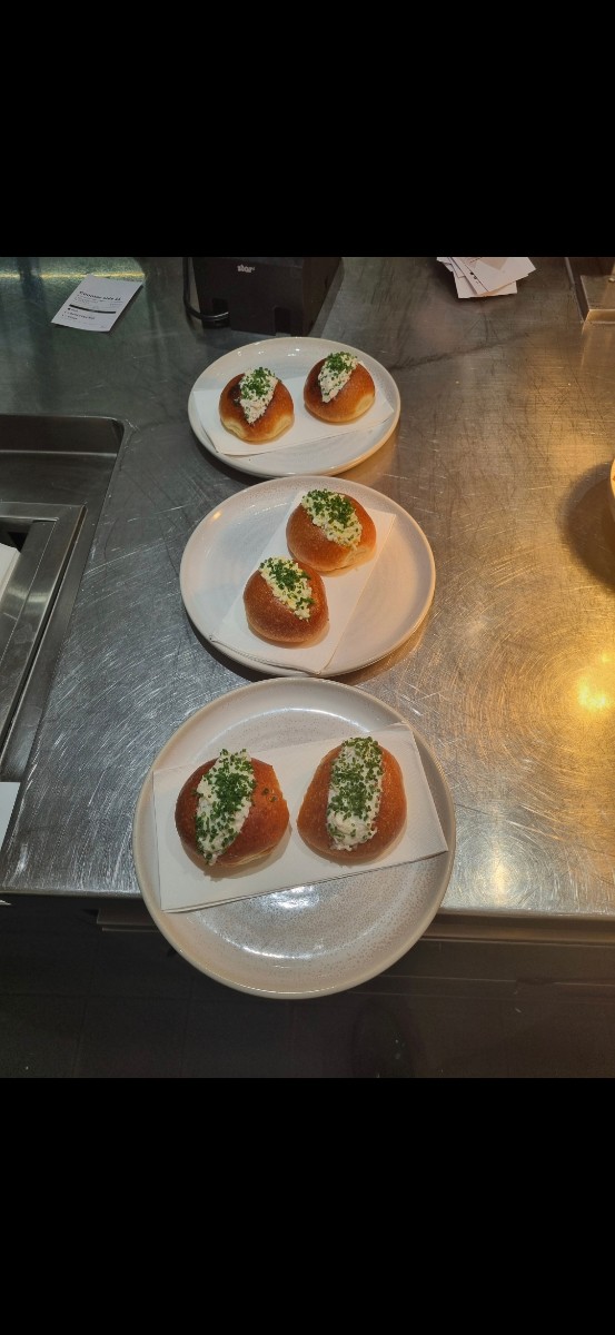 Brioche buns topped with whipped cream and fresh chives on ceramic plates