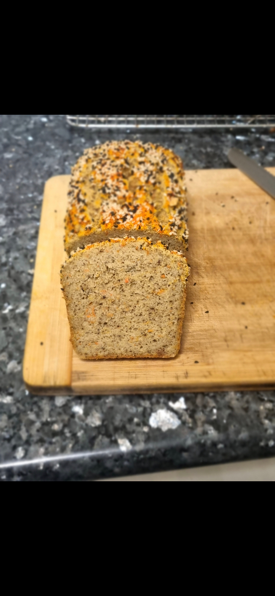 Freshly baked seeded bread loaf sliced on a wooden cutting board