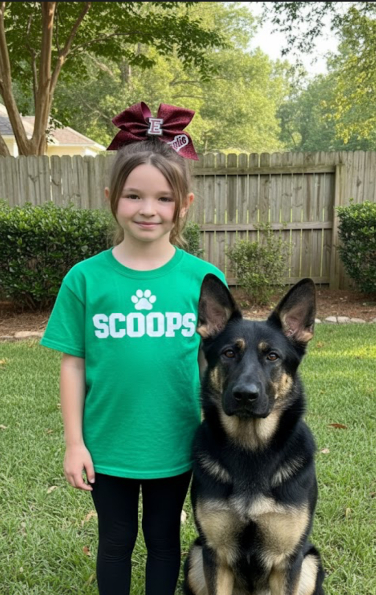 Young girl with Scoops t-shirt and German Shepherd dog in backyard
