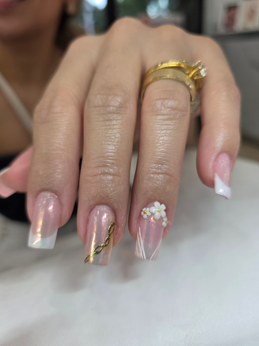 Luxurious French manicure enhanced with golden details and delicate floral decorations showcasing premium nail artistry