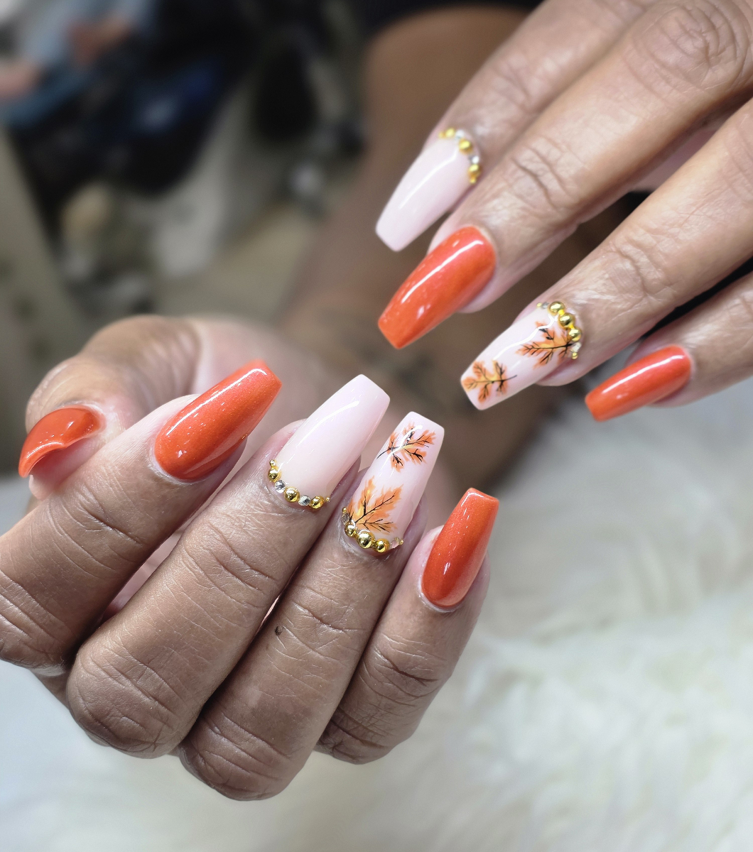 Elegant nail art in coral and pink tones with golden floral details and sophisticated decorations