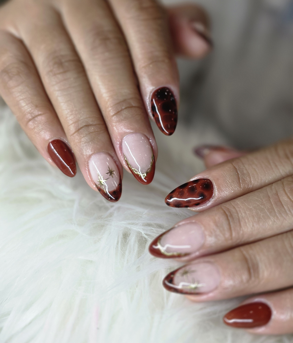 Sophisticated nail art in coral and pink tones featuring golden floral details and elegant decorative elements
