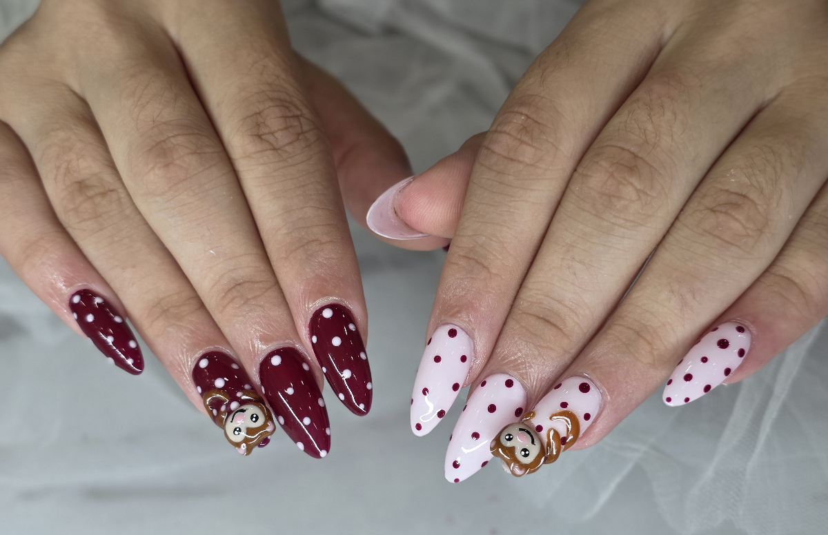Charming polka dot nail art design with burgundy and pink colors featuring cute character details and artistic flair