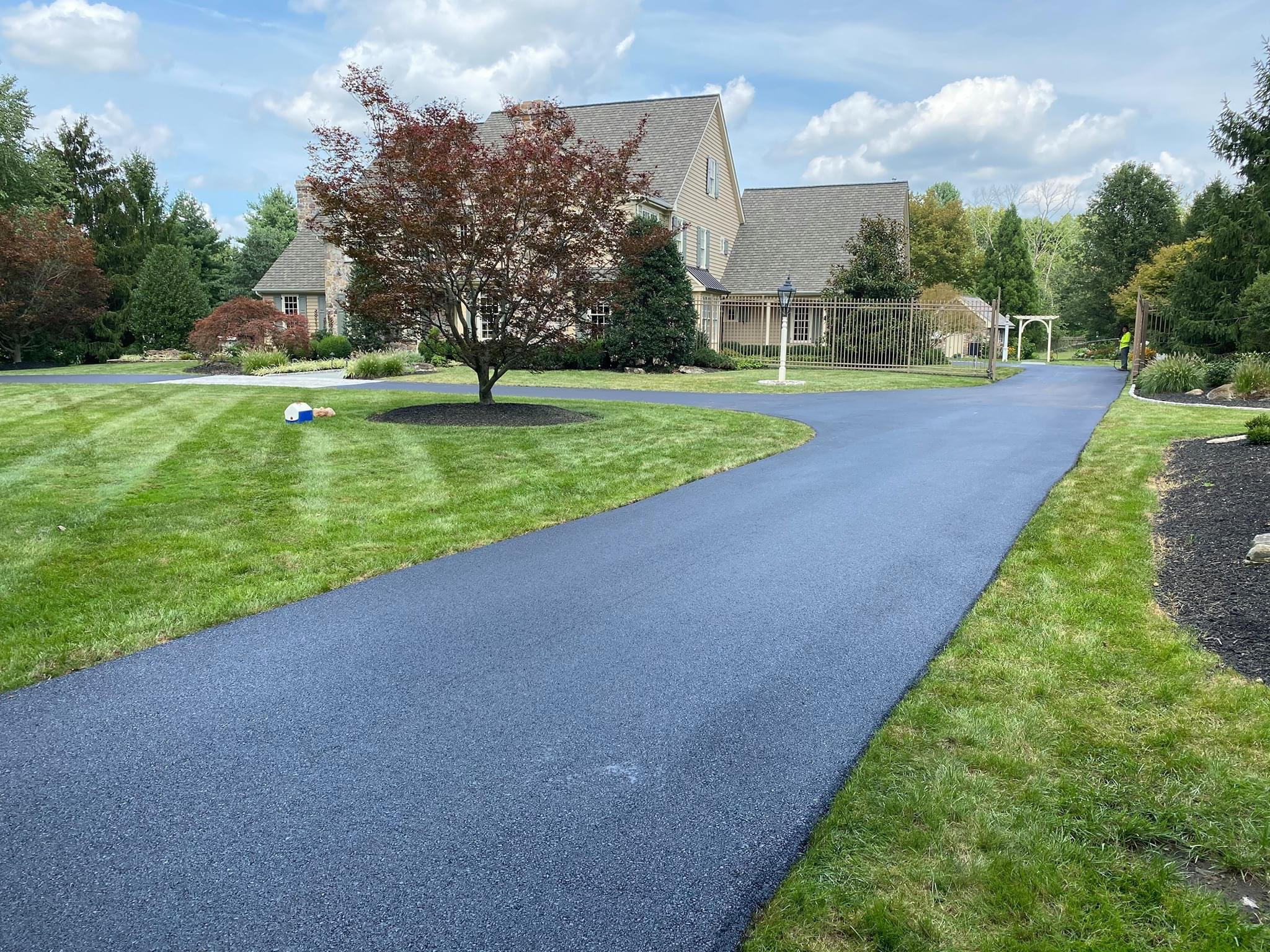 Residential driveway resurfacing project showing fresh new asphalt next to existing older surface