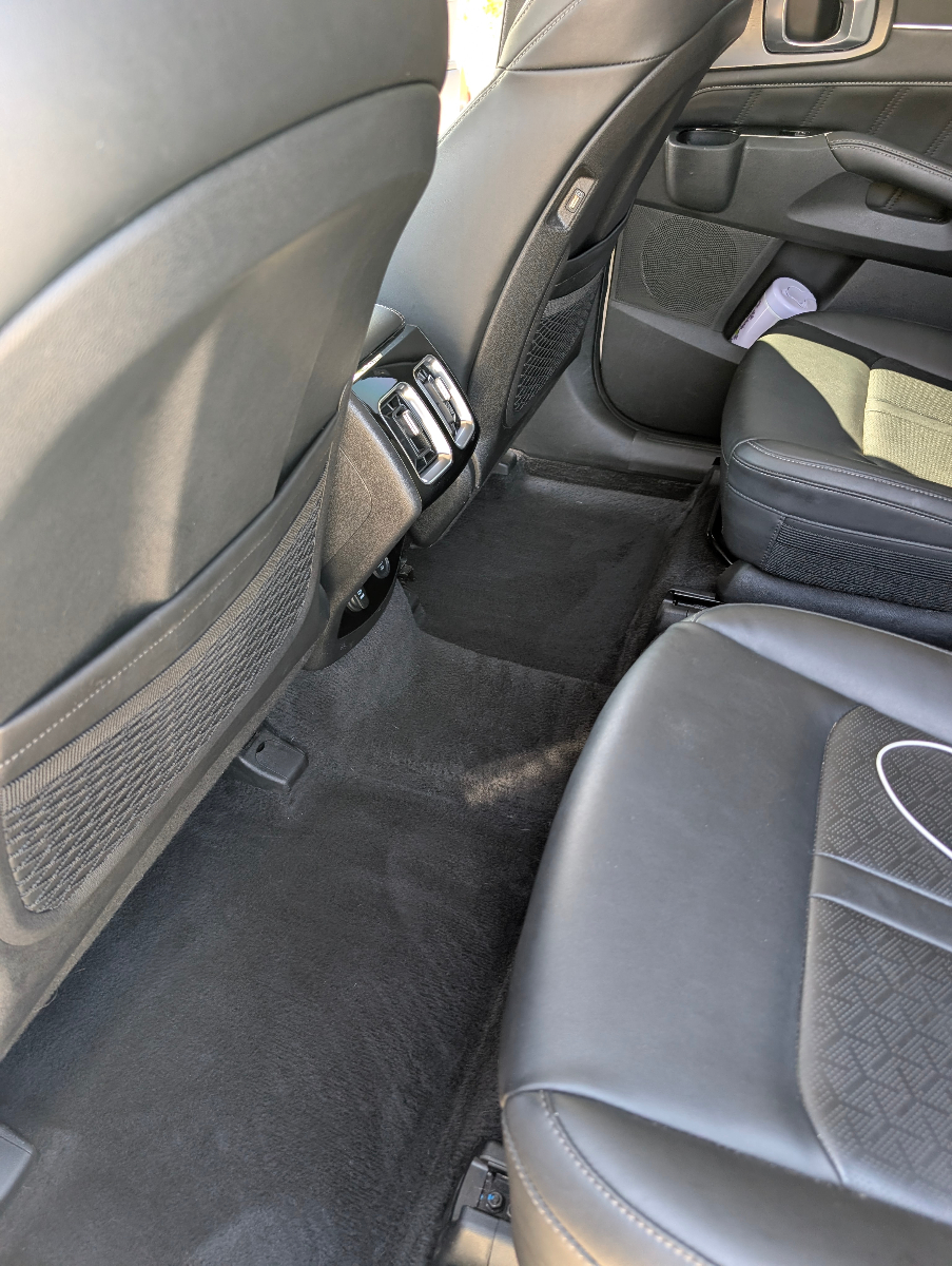 Professional interior rear seat area detailing showing pristine carpet cleaning, immaculate seat backs, and thorough attention to every detail in the cabin space