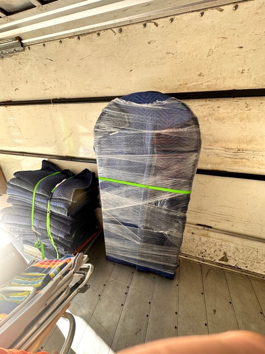 Wrapped furniture and moving blankets secured with straps inside Precision Moving truck