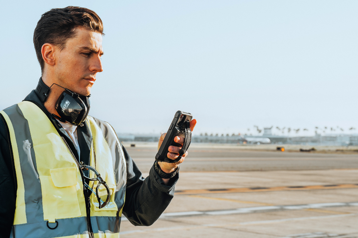 Airport ground crew worker using UAG Workflow Series case on tarmac