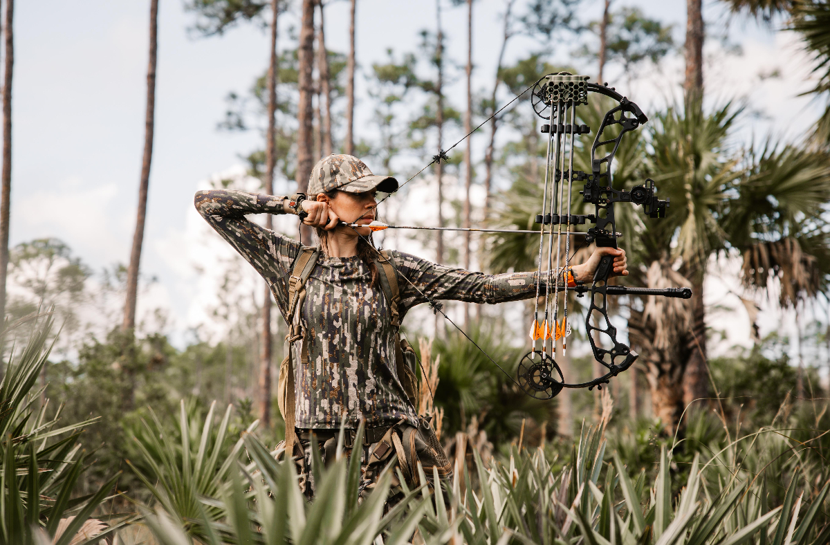 Allie with compound bow hunting in Florida wilderness
