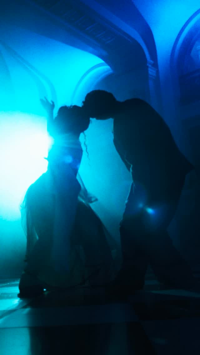 CNC: Siluetas de bailarines con iluminación azul intensa en espacio arquitectónico.