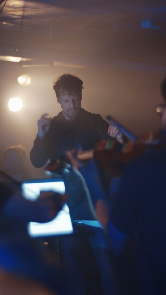 CNC: Director Paolo Bortolameolli dirigiendo en espacio inmersivo con iluminación cálida.