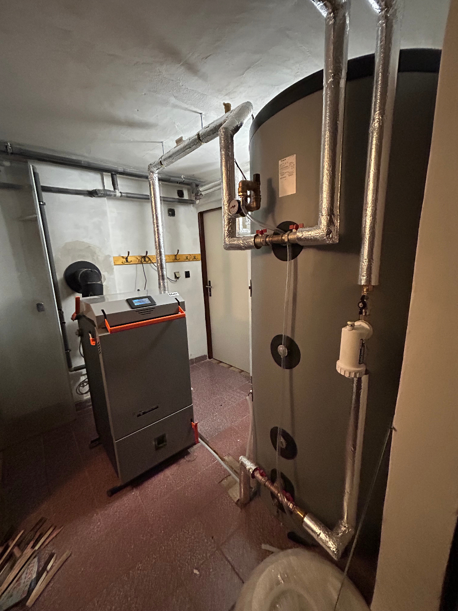 Instalace moderního plynového kotle s bojlerem a topným systémem v technické místnosti