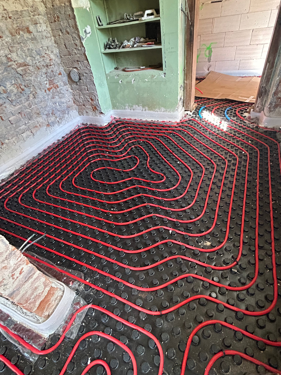 Instalace podlahového vytápění s červenými topnými trubkami v rekonstruované místnosti
