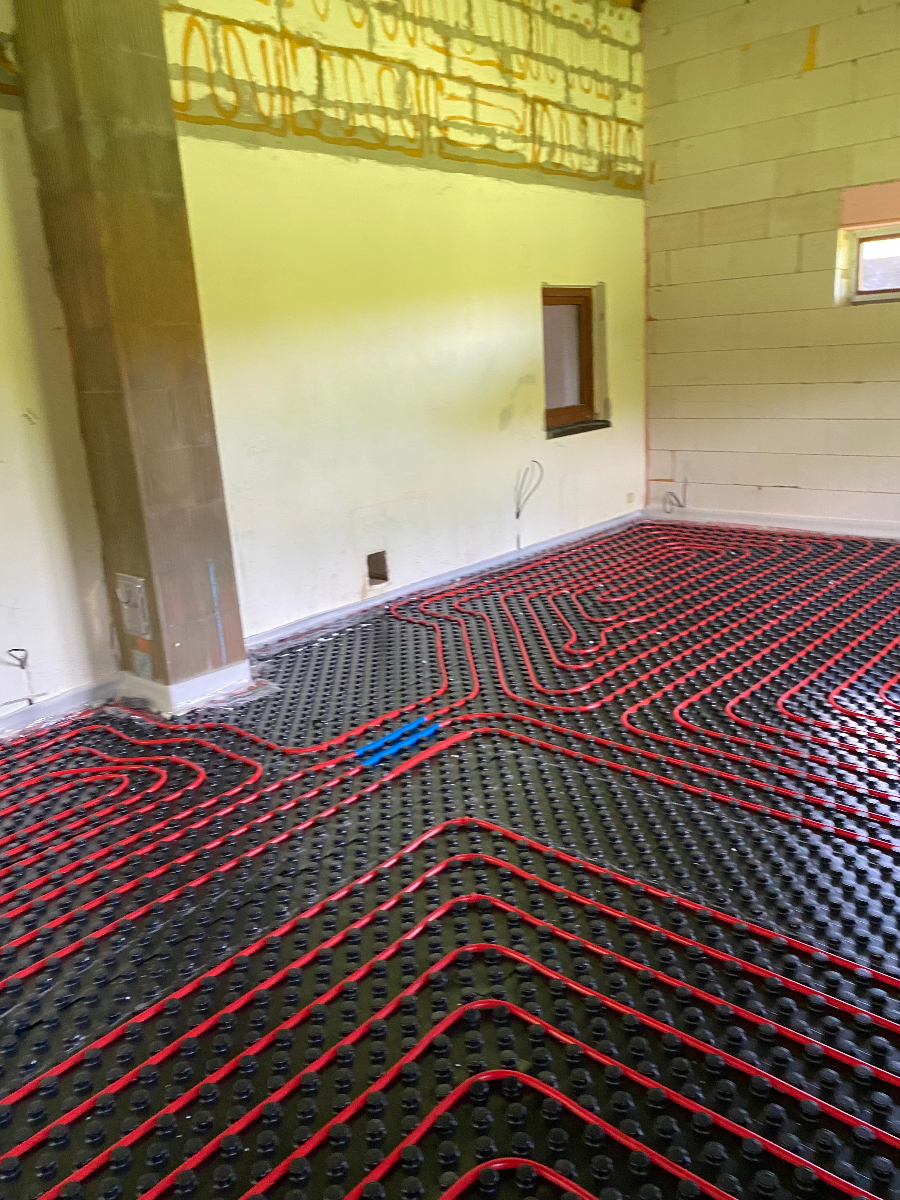 Instalace podlahového vytápění s červenými topnými trubkami na izolační podložce