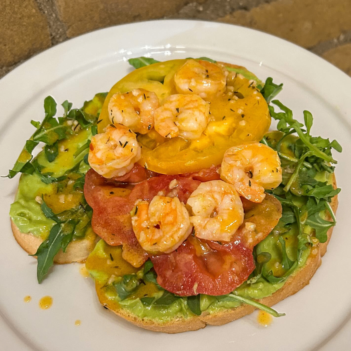Shrimp and heirloom tomato toast with arugula and avocado