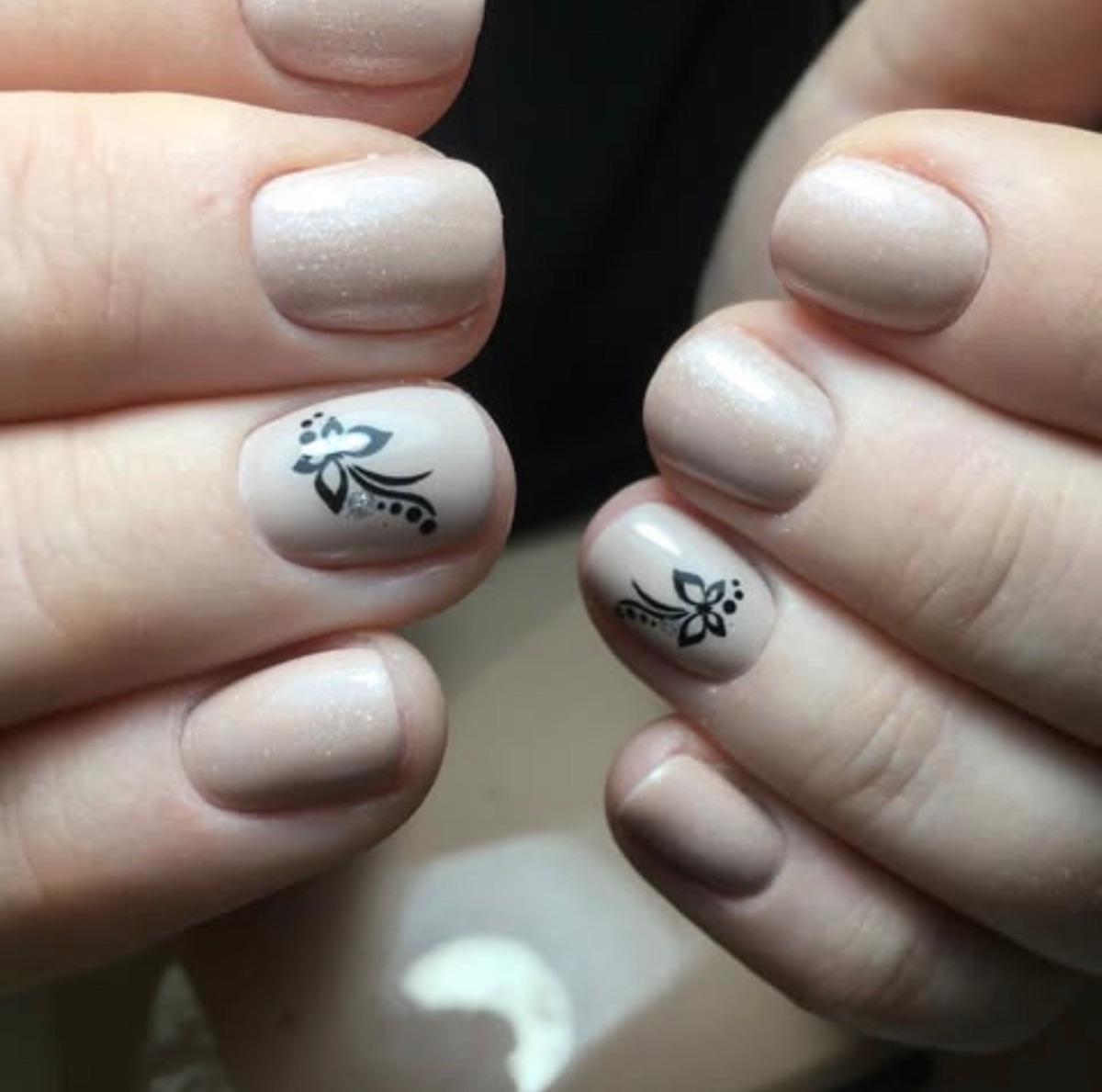 Manicura nude en uñas cortas con diseño floral negro realizada en Marbella
