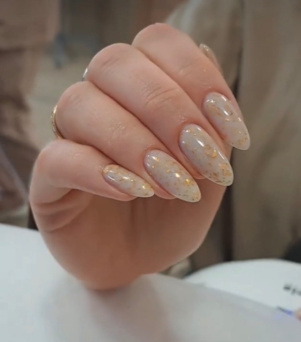 Diseño de uñas de gel nude con detalles dorados elegantes realizado en Marbella