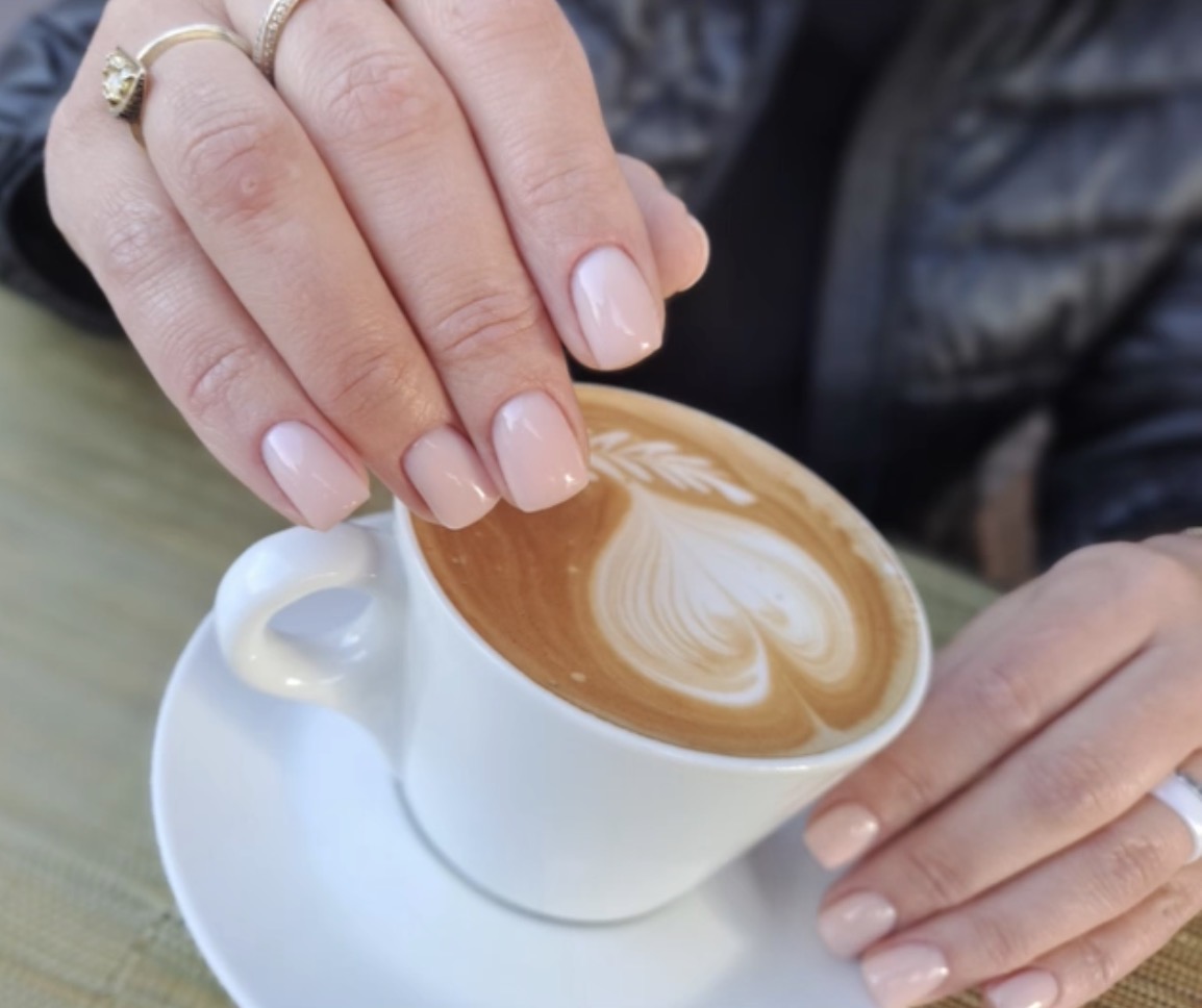 Manicura nude natural en uñas cortas mientras sostiene una taza de café en Marbella