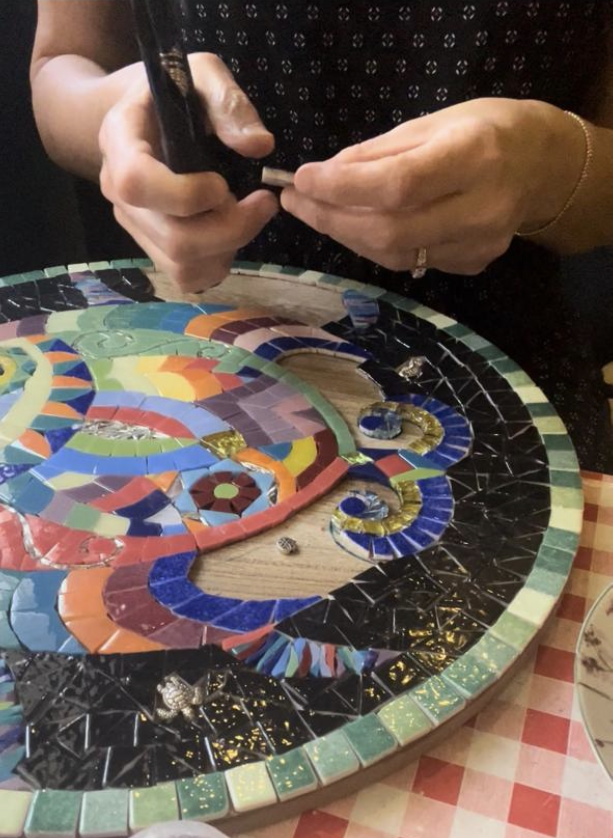 Artisan hands arranging mosaic tile fragments in workshop