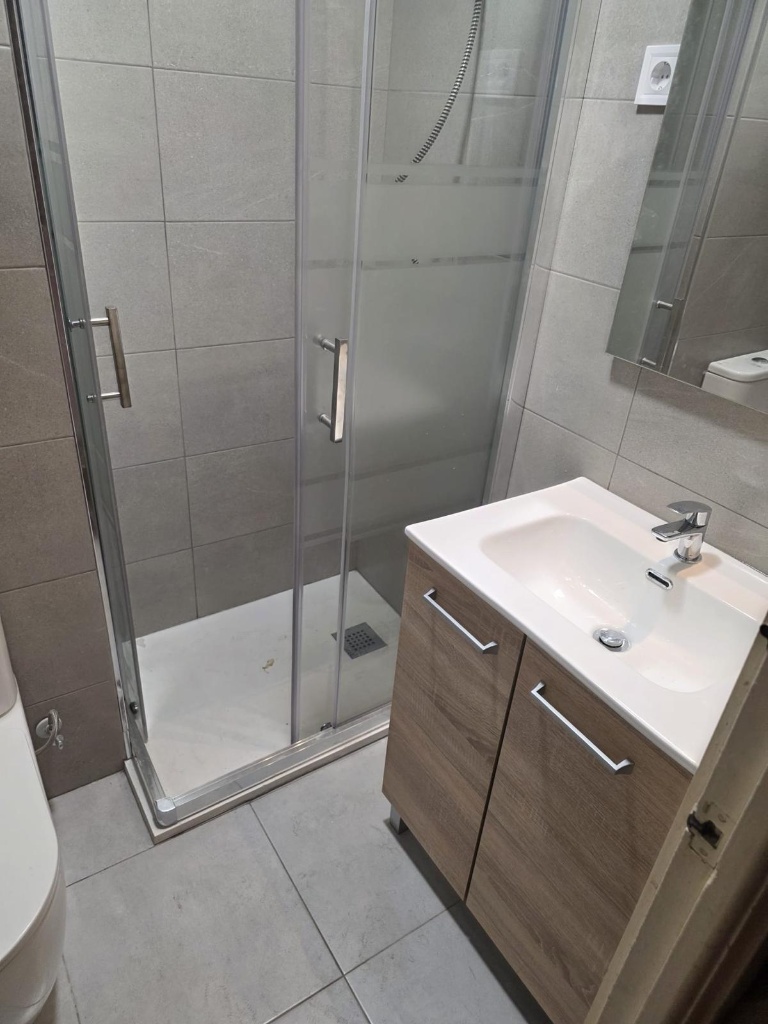 Baño moderno reformado con azulejos estilo mármol blanco y mueble gris oscuro