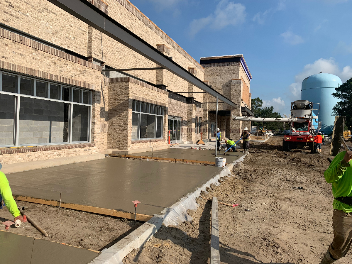 Commercial concrete sidewalk installation Charleston SC - professional crew pouring fresh concrete for durable pedestrian walkway at commercial building site