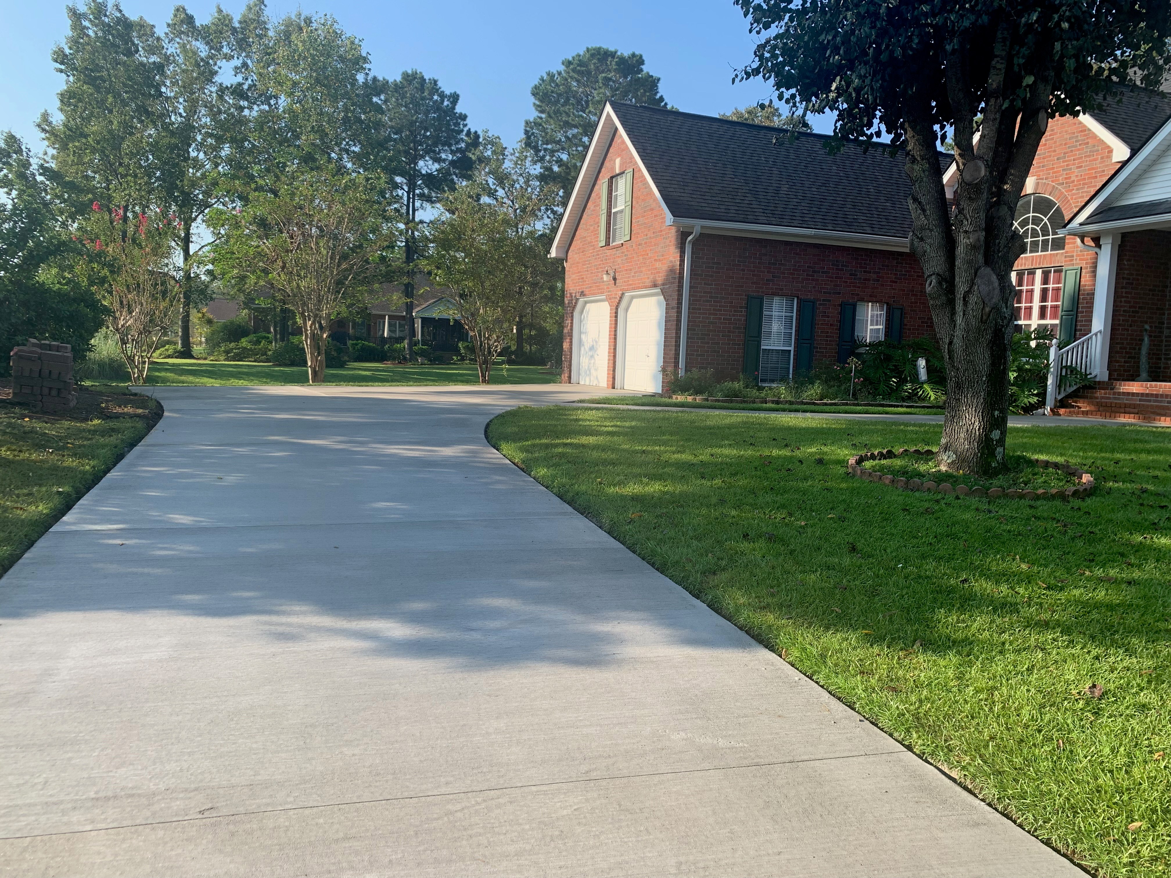 Concrete Driveway with Brick Border - West Ashley SC Concrete driveway with brick border in West Ashley SC featuring smooth broom finish main surface, decorative stamped brick pattern border accent, contrasting earth-tone colors, proper expansion joints, and professional installation for enhanced residential curb appeal in Charleston
