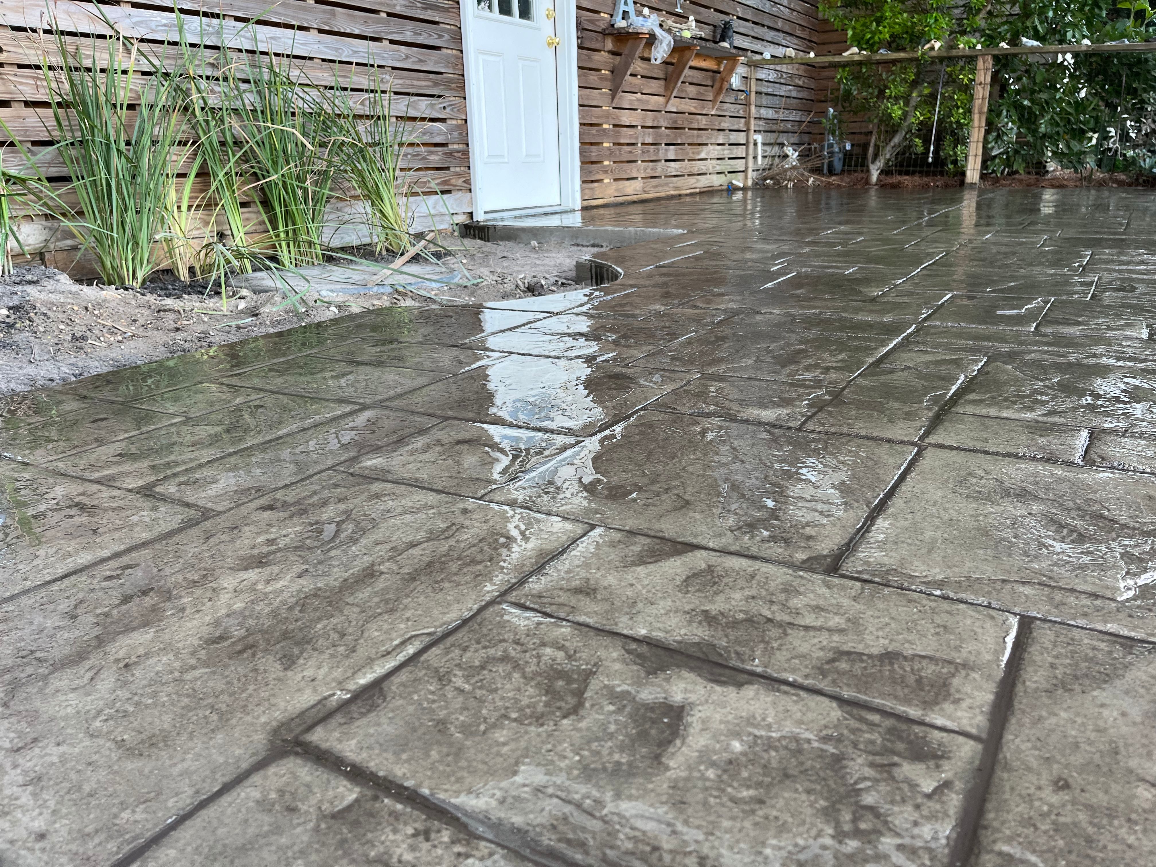 Outdoor Patio Entertainment - Charleston SC Decorative Concrete Outdoor patio entertainment area in Charleston SC with decorative stamped concrete surface, gas BBQ grill, dining furniture with umbrella, and family gathering space showcasing modern patio design trends and functional outdoor living in Lowcountry