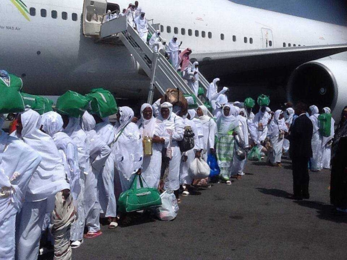 Groupe de pèlerins en tenue d'ihram embarquant pour le Hadj